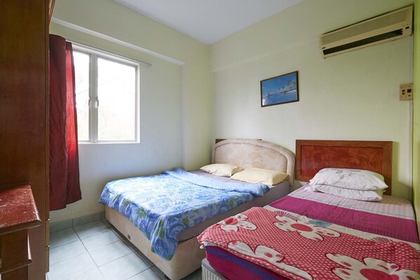 A bedroom with two beds, a window, an air conditioner, and a painting on the wall.