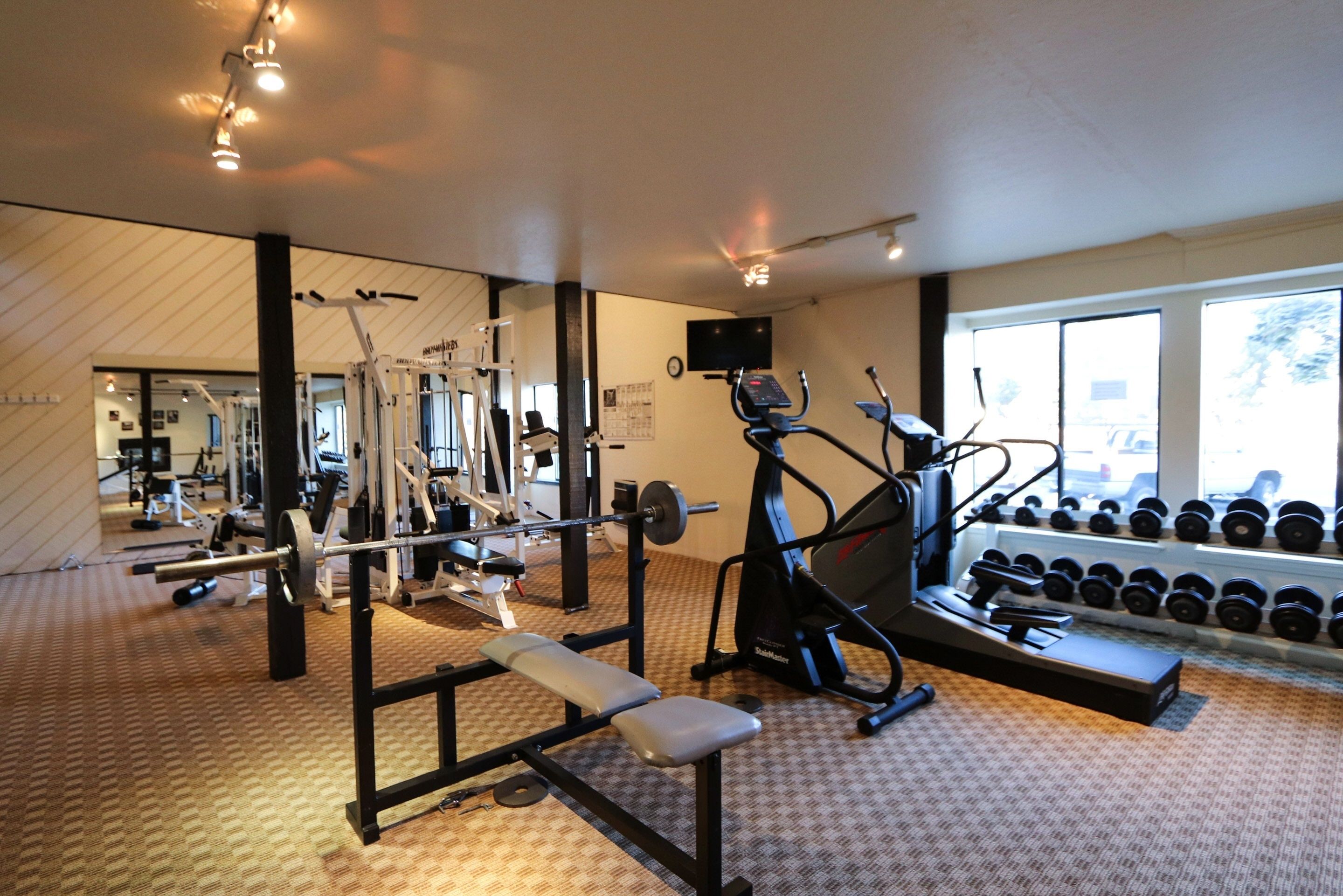 A gym with exercise equipment, a bench, and dumbbells.