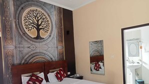 A hotel room with a bed, a nightstand, a wall-mounted mirror, and a bathroom visible through an open door. - Kangs Nirvana Resorts and Spa (Garhshankar)