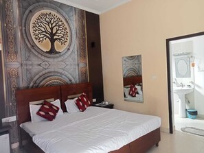 A hotel room with a bed, a nightstand, a wall-mounted mirror, and a bathroom visible through an open door. - Kangs Nirvana Resorts and Spa (Garhshankar)