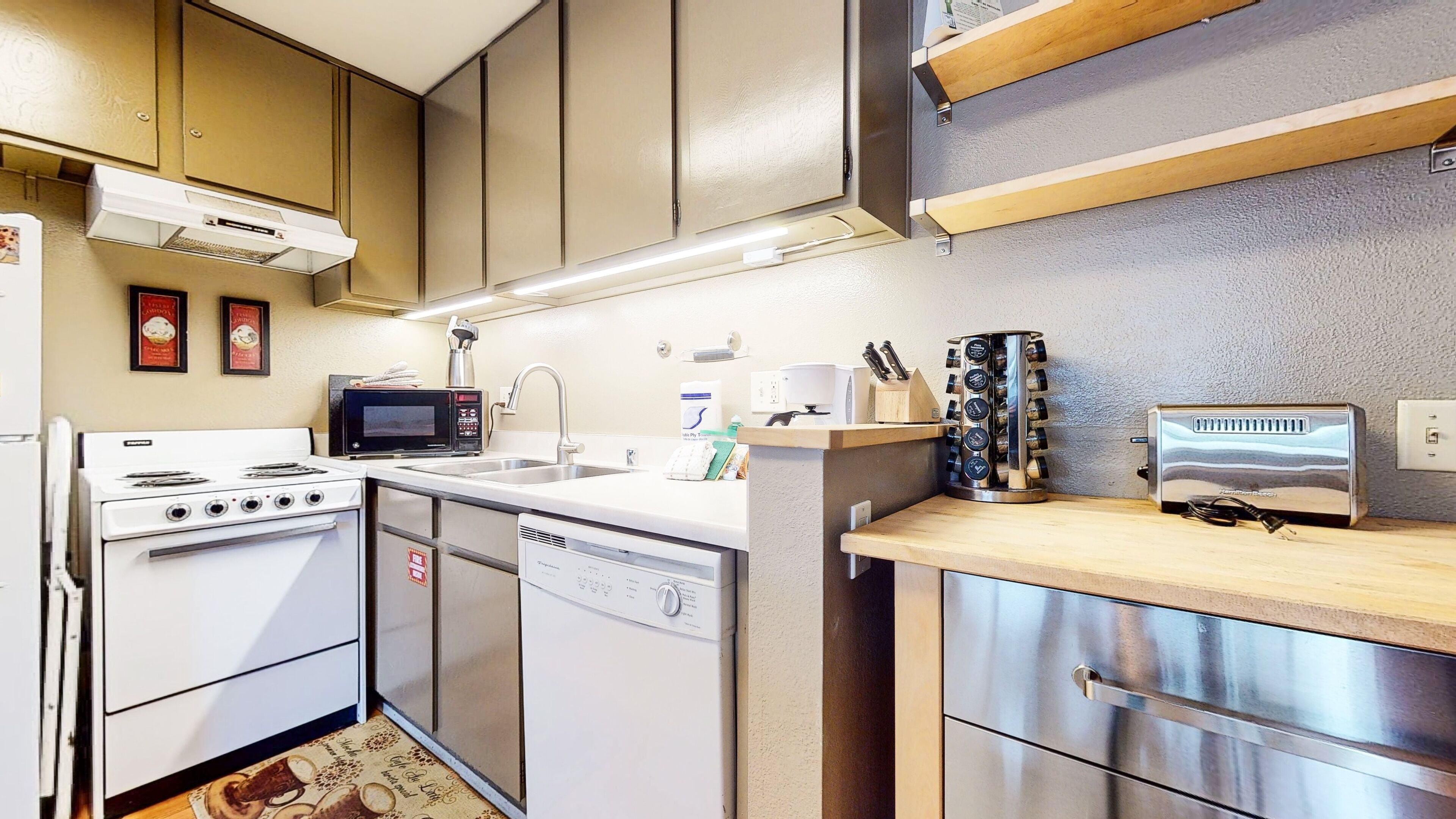 A compact kitchen with a stove, microwave, sink, and modern appliances.
