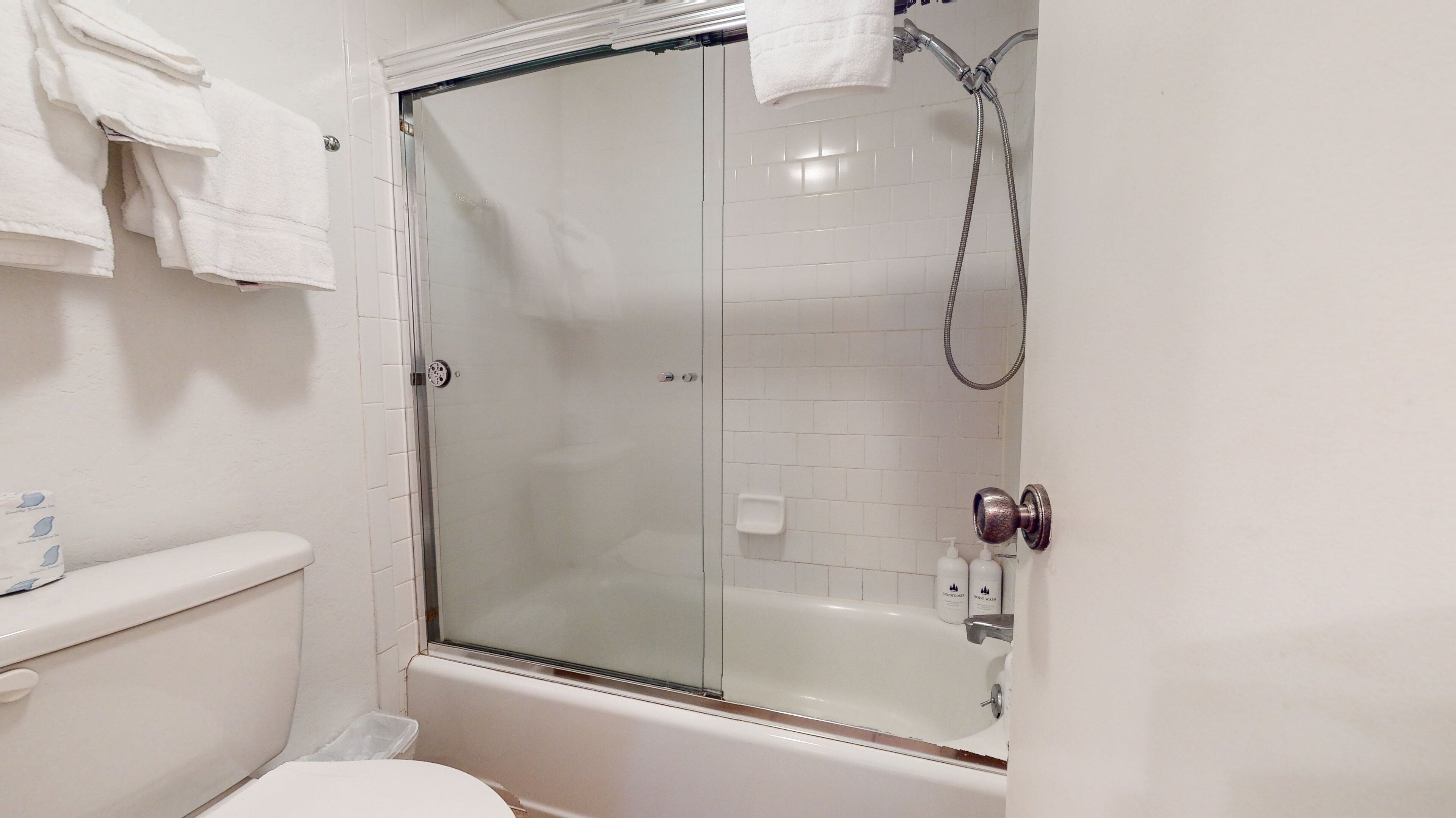 A bathroom with a glass-enclosed shower, a toilet, and a bathtub.