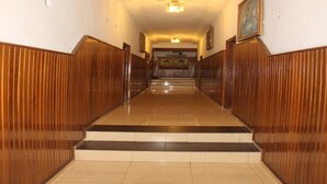 Un pasillo con paneles de madera y suelo de baldosas que conduce a una escalera.