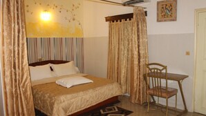 Un dormitorio con cama, una silla, un escritorio y aire acondicionado instalado en la pared.