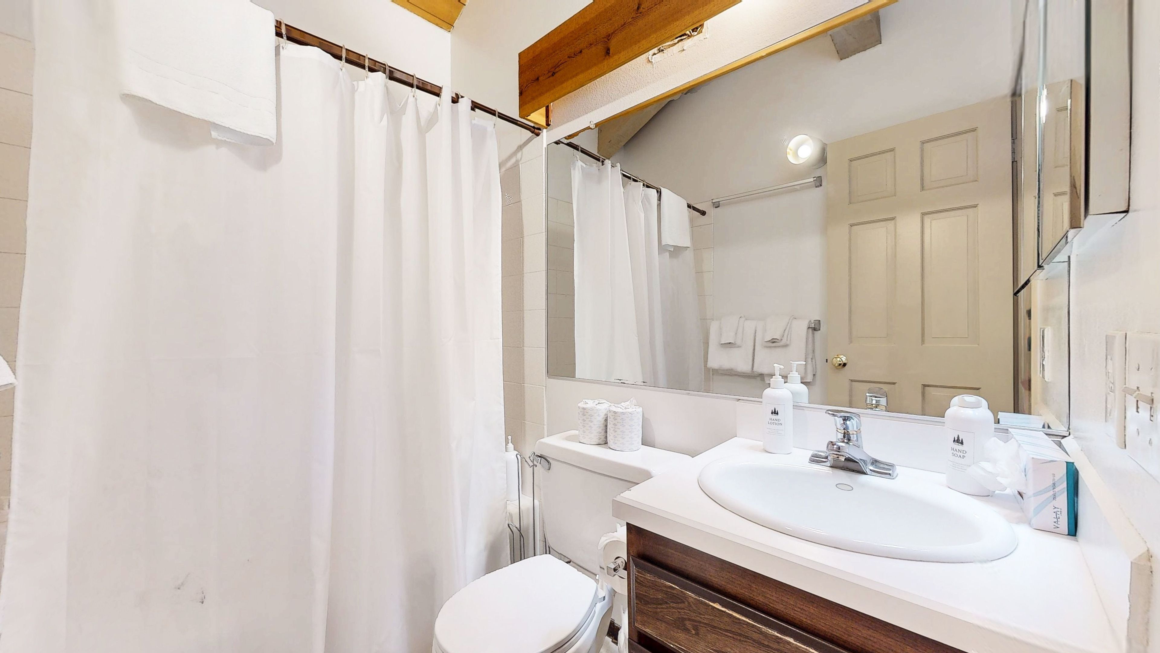 A bathroom with a white sink, mirror, and shower curtain.