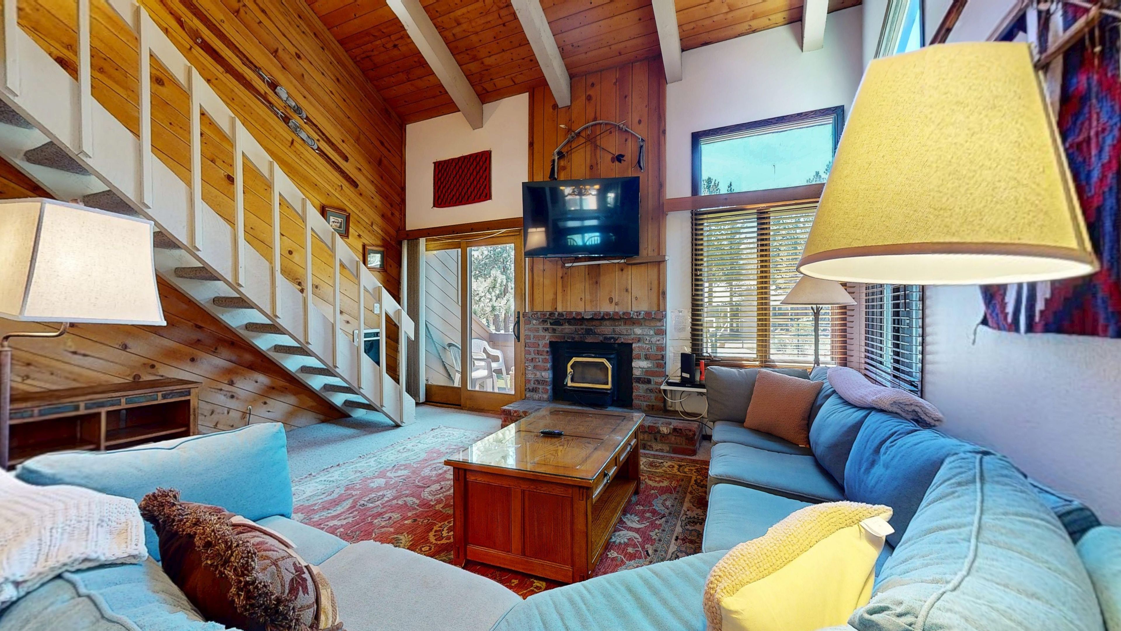 Ein gemütliches Wohnzimmer mit Kamin, Treppe und Fernseher.