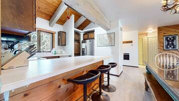 A kitchen with wooden cabinets, a large island with stools, and a hanging light fixture.