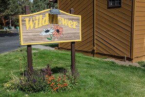 A wooden sign with the text "Wildflower" and illustrations of flowers. - Wildflower #6 2 Bedroom Condo (Mammoth Lakes)
