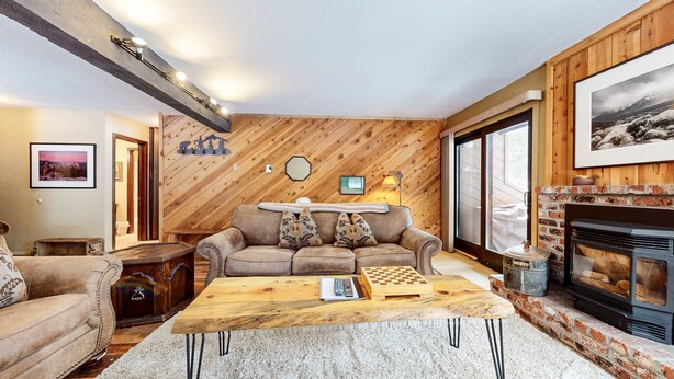 A cozy living room with a wooden wall, a fireplace, a sofa, and a coffee table.