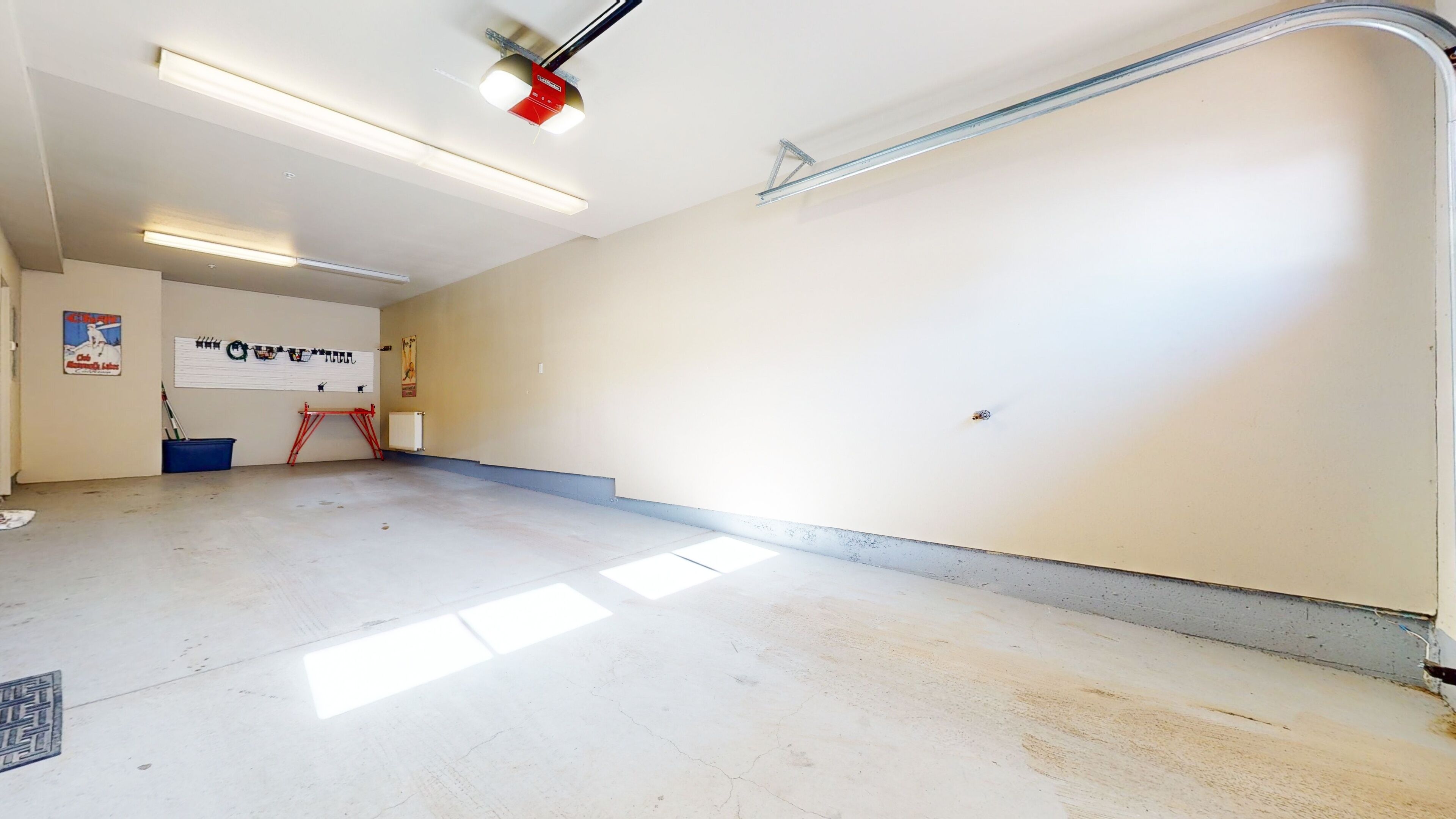 A spacious room with white walls, a visible ceiling light fixture, and a radiator.