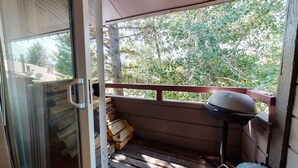 A wooden deck with a grill and stacked firewood. - Sierra Manors 8 Pet-Friendly, Short Walk to the Shuttle, Spacious, Centrally Located by RedAwning (Mammoth Lakes)