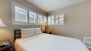 A bedroom with a bed, two bedside tables, a lamp, and two windows with blinds. - Sierra Manors 8 Pet-Friendly, Short Walk to the Shuttle, Spacious, Centrally Located by RedAwning (Mammoth Lakes)