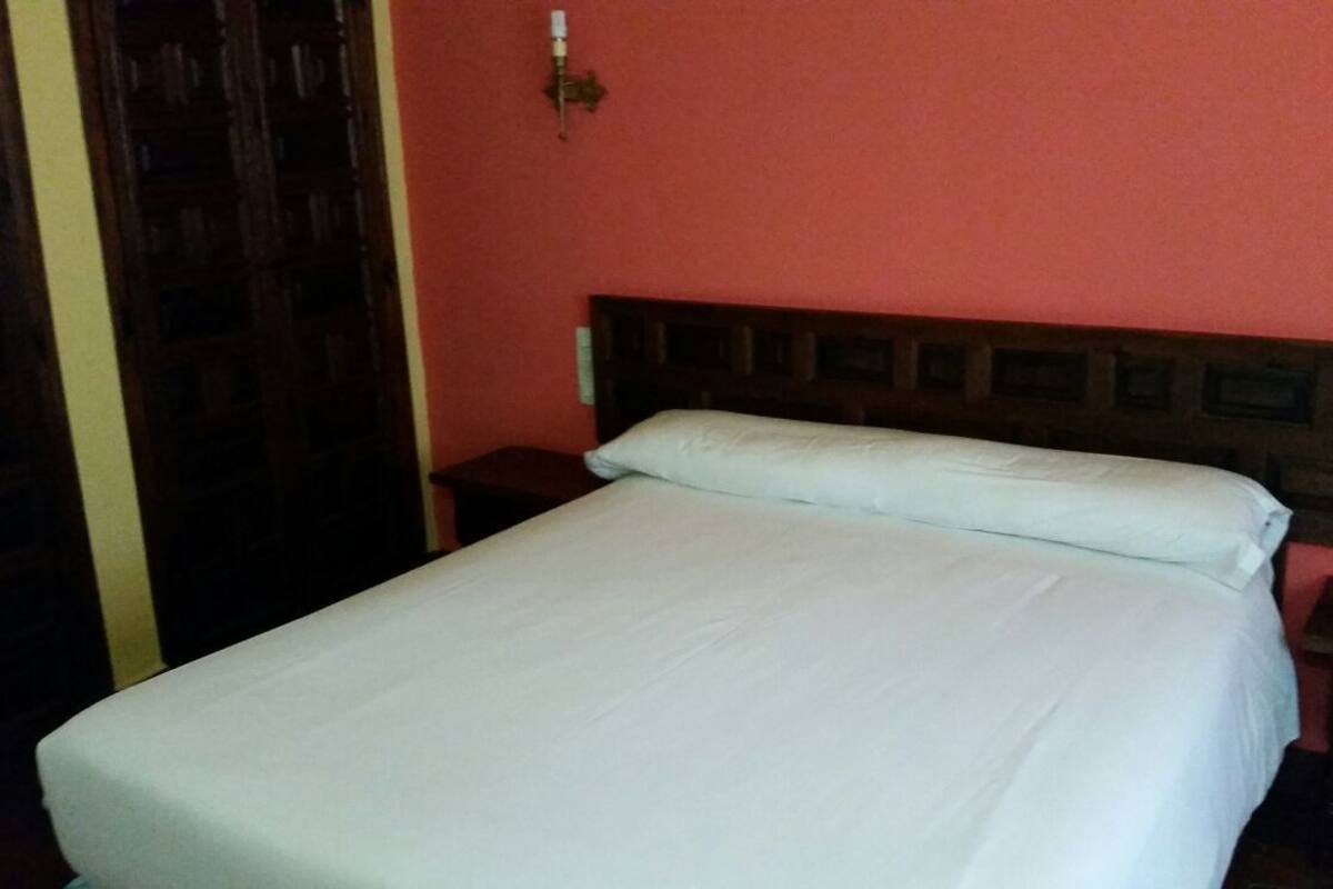 Ein Bett mit Holz-Kopfteil in einem Zimmer mit roter Wand.
