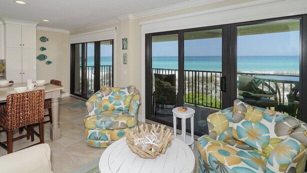 A spacious balcony with a view of the ocean, furnished with wicker chairs and a round table. - Waters Edge 110n 2 Bedroom Condo by RedAwning (Holmes Beach)