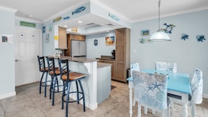 A kitchen with a central island, bar stools, and a dining table with chairs. - The S 2a 1 Bedroom Villa by RedAwning (Holmes Beach)