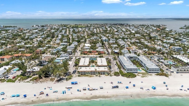 An aerial view of a coastal resort with a sandy beach, multiple bungalow-style accommodations, and a central circular area with a pool. - The S 2a 1 Bedroom Villa by RedAwning (Holmes Beach)
