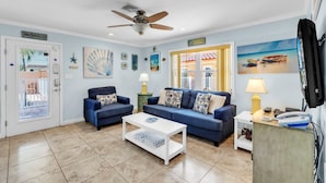 A living room with two sofas, a coffee table, a ceiling fan, and artwork on the walls. - The S 2a 1 Bedroom Villa by RedAwning (Holmes Beach)