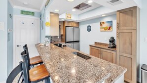 A modern kitchen with granite countertops, stainless steel appliances, and wooden cabinets. - The S 2a 1 Bedroom Villa by RedAwning (Holmes Beach)