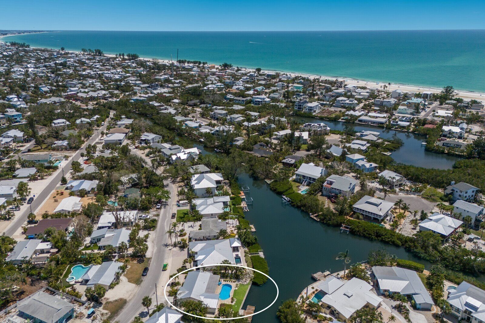 Luchtbeeld van een kustgebied met woonhuizen, een strand en een jachthaven.