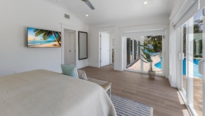 A bedroom with a bed, a ceiling fan, a large window, and a view of a pool.