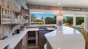 A modern kitchen with a large island, a view of the outdoors, and a 'FREE DRINKS' sign.