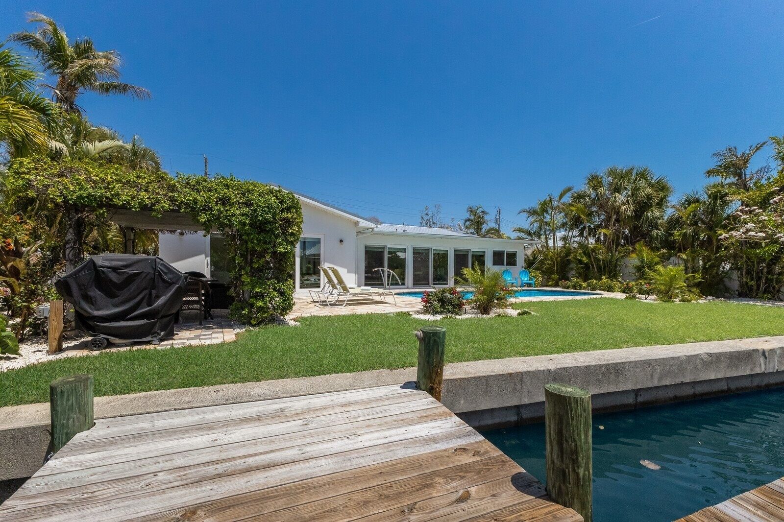 Una casa moderna con piscina, asador techado y terraza de madera.