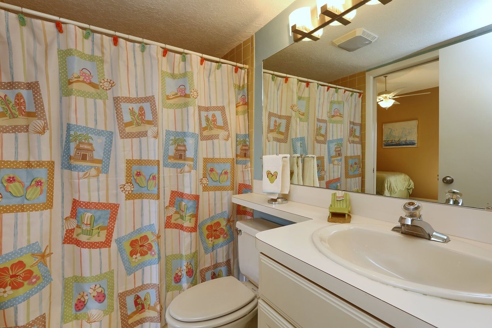A bathroom with a striped shower curtain, a toilet, a sink with a mirror, and a towel rack.