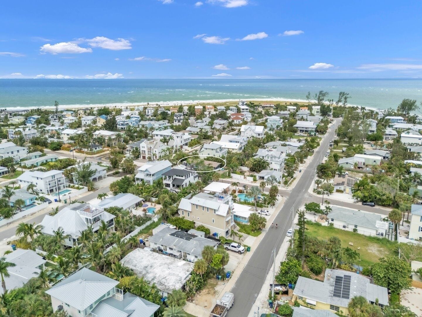 Zona residencial costera con casas, una avenida principal y una playa al fondo.