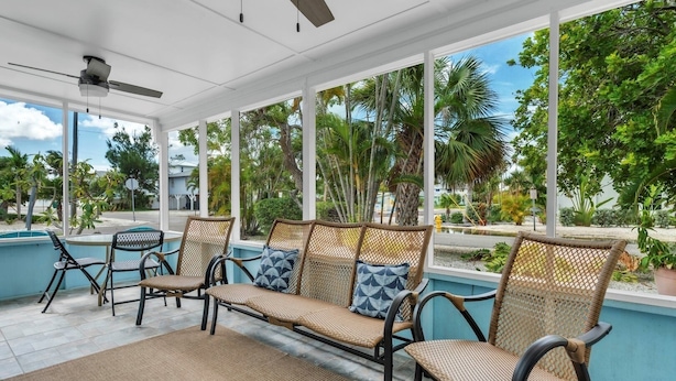 A covered outdoor seating area with wicker furniture and a ceiling fan. - Minnow 1 1 Bedroom Cottage by RedAwning (Anna Maria)