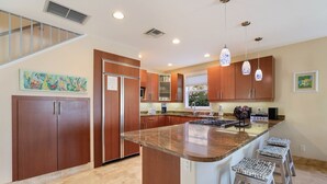 A modern kitchen with a large island, wooden cabinets, and pendant lighting. - Blue Water Escape 3 Bedroom Villa by RedAwning (Bradenton Beach)