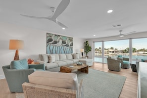 A modern living room with a sofa, chairs, a coffee table, and a large window with a view of a pool and resort.