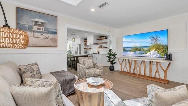 Una sala de estar moderna con un sofá, sillones, una mesa de centro y un televisor sobre un mueble.