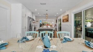 Comedor con isla central, muebles blancos y vista al área de estar.