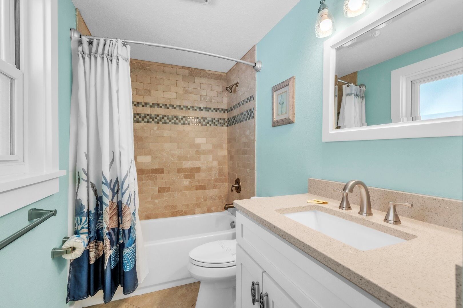 A bathroom with a shower, toilet, sink, and a mirror.