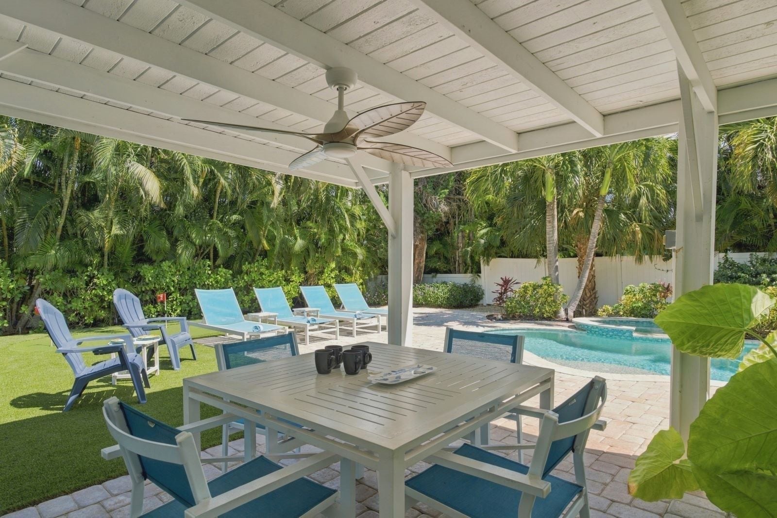 An outdoor patio with a pool, lounge chairs, and a table with chairs.