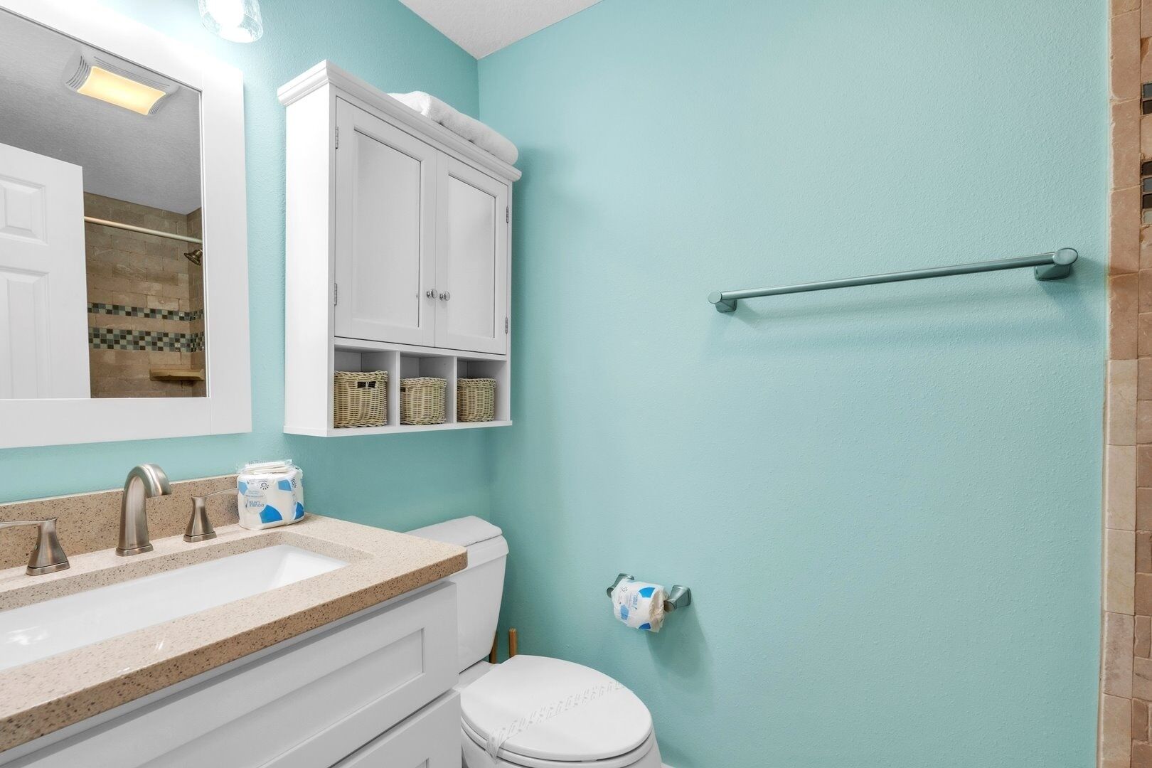 Un baño con tocador blanco, lavabo, inodoro y zona de ducha.