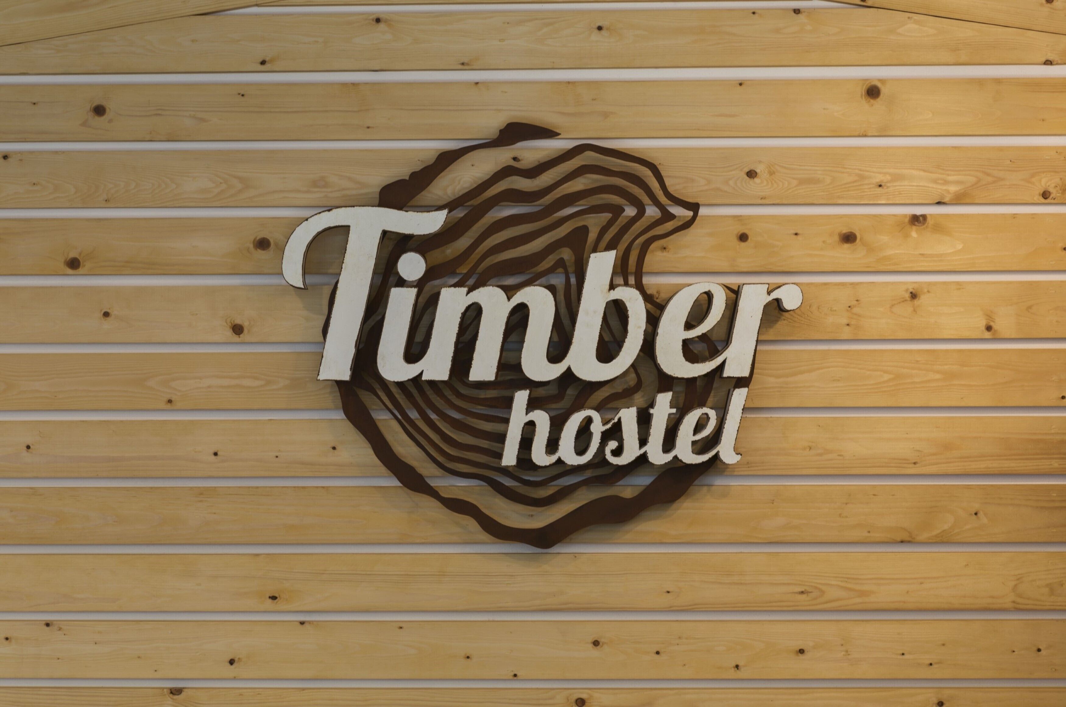 Pared de madera con un letrero que dice 'Timber hostel'.