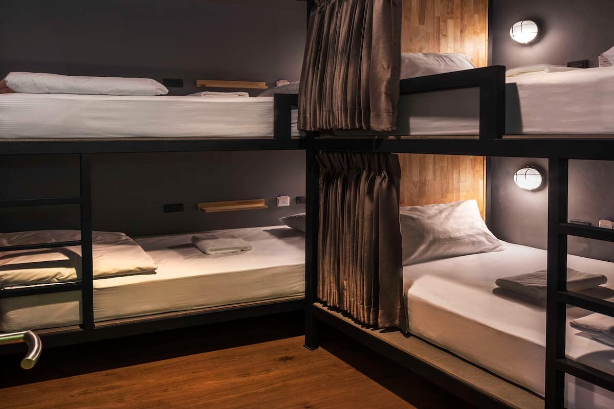 A bunk bed room with wooden floors, a door with a handle, and a wall-mounted light fixture.
