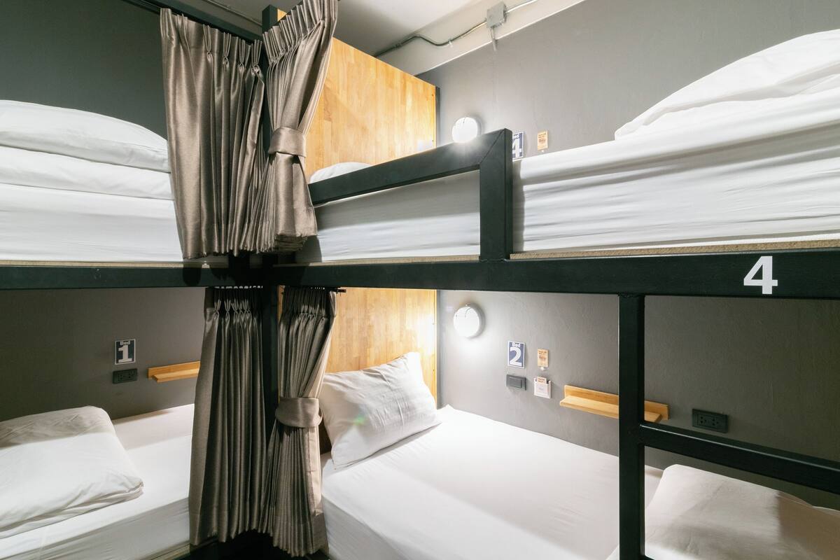 A bunk bed room with curtains, a wooden headboard, and numbered beds.