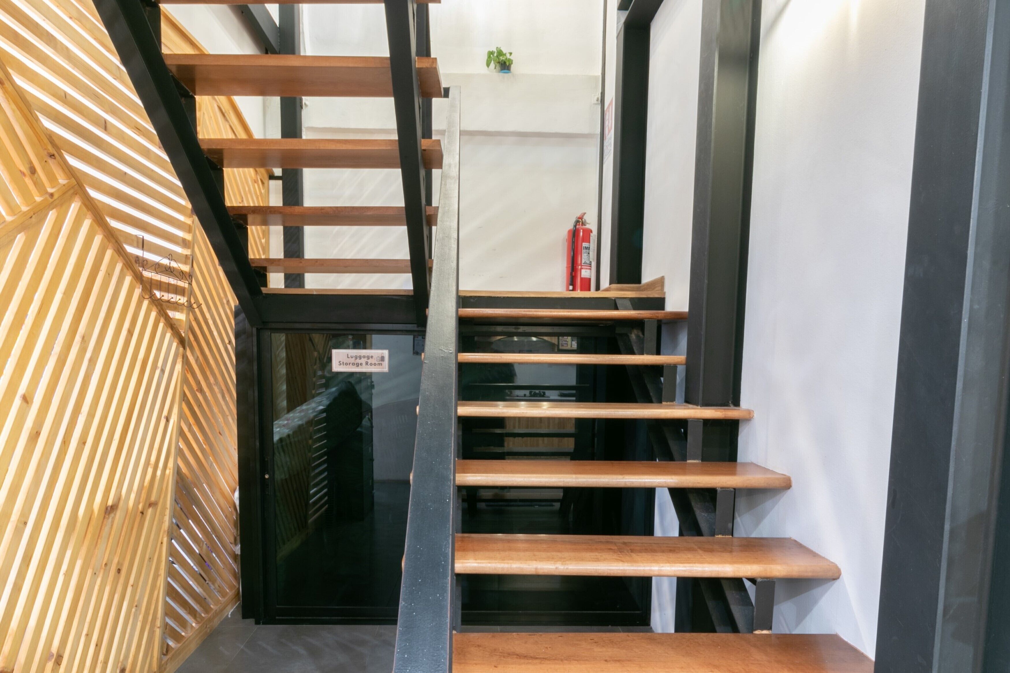 Una escalera con escalones de madera y barandillas de metal, que conduce a un cuarto de almacenamiento.