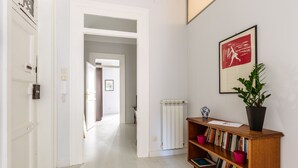 A hallway with a wooden bookshelf, a radiator, and a framed picture on the wall. - Casa Dante with Balcony by Wonderful Italy (Palermo)