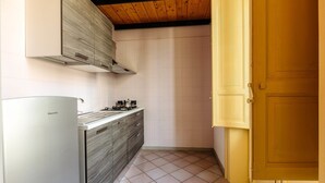 A compact kitchen with a built-in refrigerator, a gas stove, and a wooden ceiling. - Casa Dante with Balcony by Wonderful Italy (Palermo)