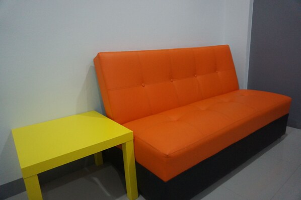 A room with a sofa and a small table. - The Amber Mansion (Roi Et)