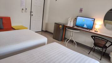 A hotel room with two beds, a desk with a computer, a chair, and a TV displaying a scenic view.