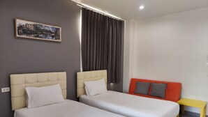 A hotel room with two beds, a small table, and a painting on the wall. - The Amber Mansion (Roi Et)
