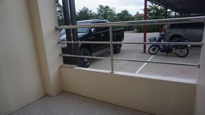 A view from a window with metal bars, a tiled floor, and parked vehicles outside. - The Amber Mansion (Roi Et)