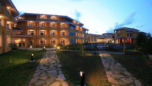 A multi-story hotel with a stone pathway leading to the entrance, surrounded by well-maintained lawns and a small pond. - Blue Orange Beach Resort (Sozopol)