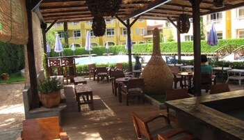 An outdoor patio area with wooden furniture, umbrellas, and a decorative tree.