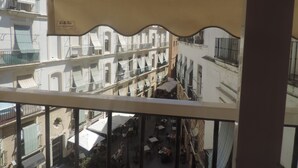 A view from a balcony overlooking a courtyard with outdoor seating and multiple buildings. - Hostal Bahía (Cádiz)