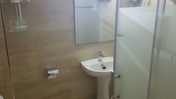 A bathroom with a toilet, sink, and glass shower enclosure.